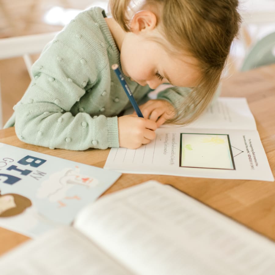 blonde girl drawing in a bible Journal for kids with an open bible nearby
