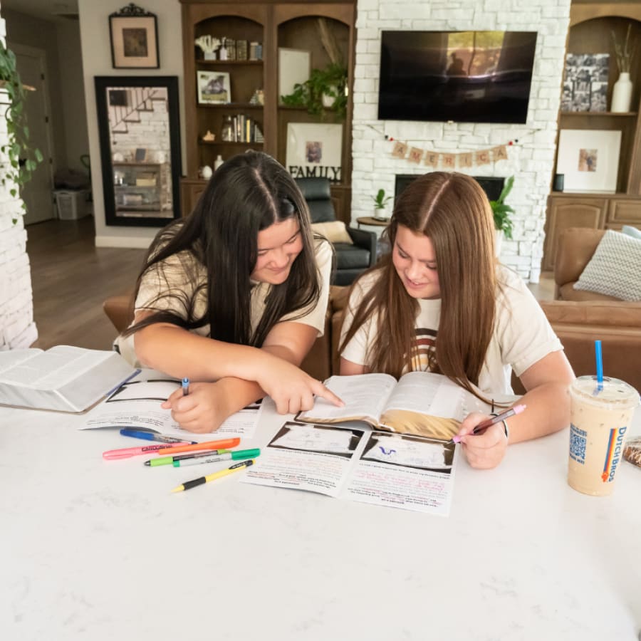 two teens at a table reading a guided bible study for teens