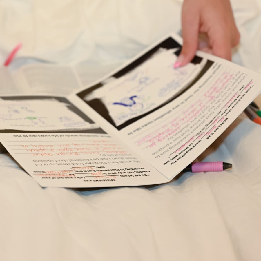 girl holding a bible study for teens on her bed with an open bible